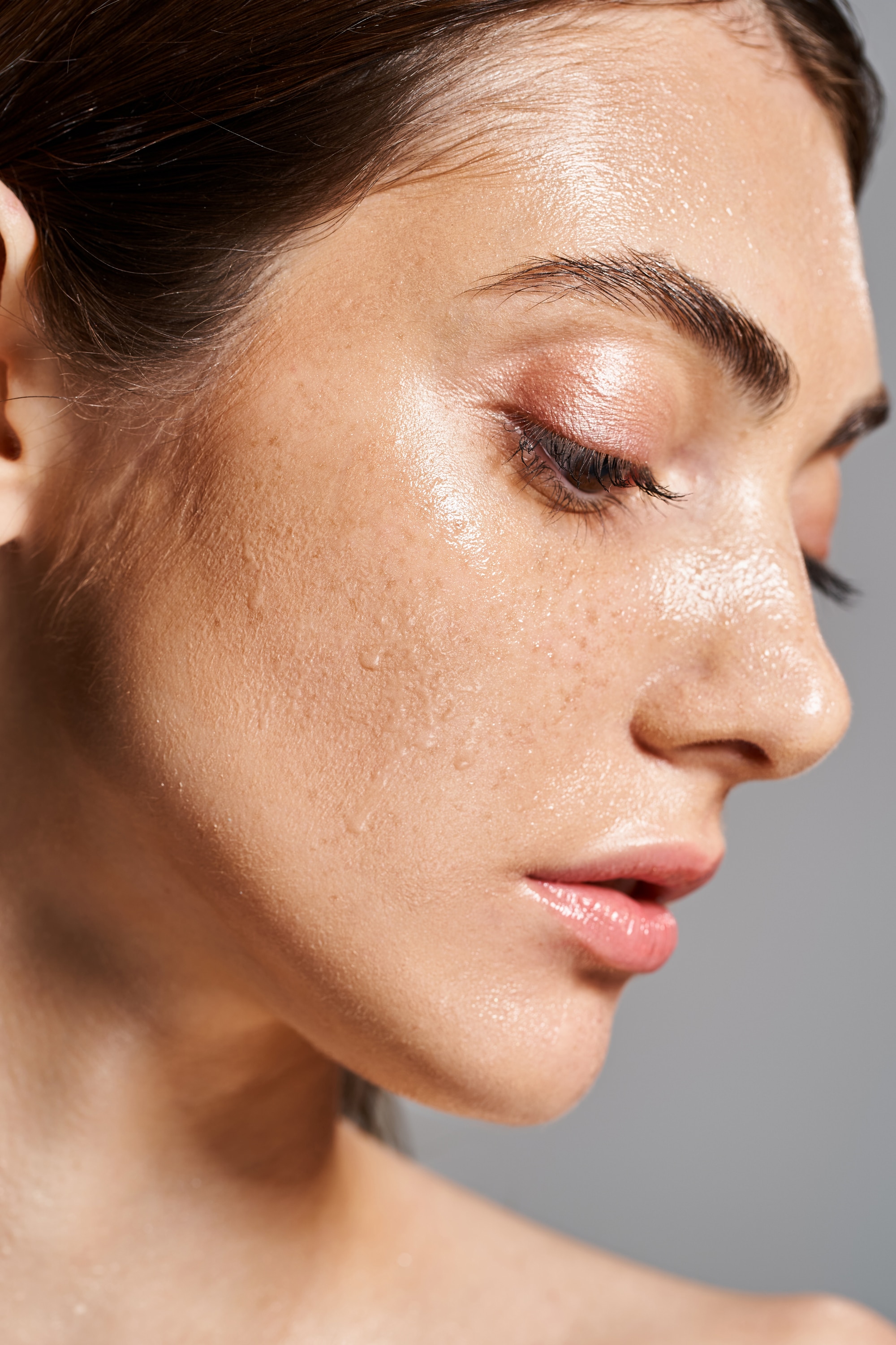 A young Caucasian woman with water drops on her face, exuding a sense of serenity and connection with nature.
